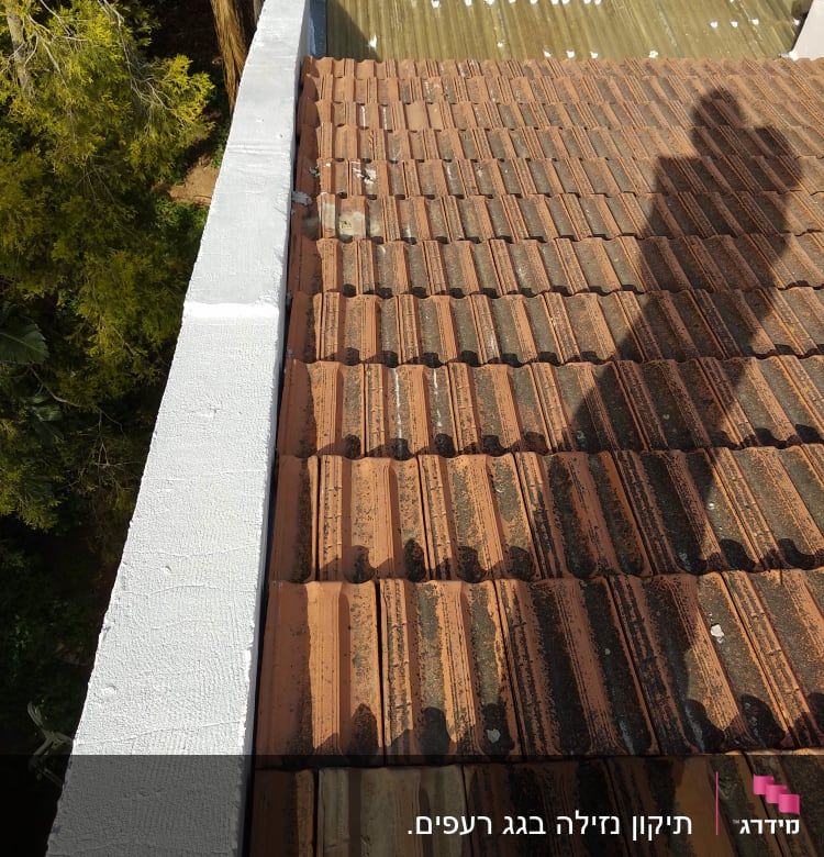 גג רעפים חום עם צל אדם על הגג